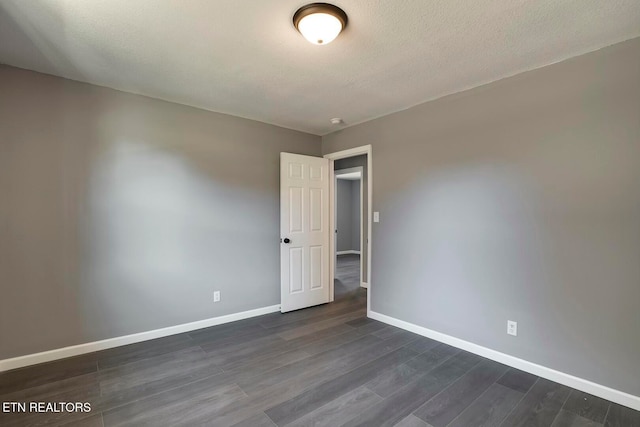 spare room featuring a textured ceiling and dark wood-type flooring