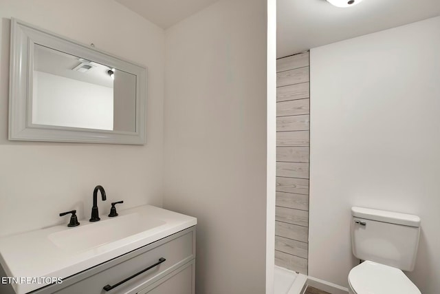 bathroom featuring vanity, toilet, and walk in shower