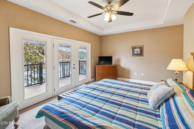 carpeted bedroom with access to exterior, french doors, a tray ceiling, and ceiling fan