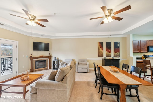 carpeted living room with a tray ceiling, ceiling fan, and crown molding