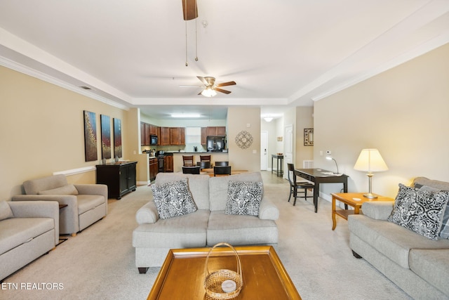 carpeted living room featuring a raised ceiling, ceiling fan, and ornamental molding