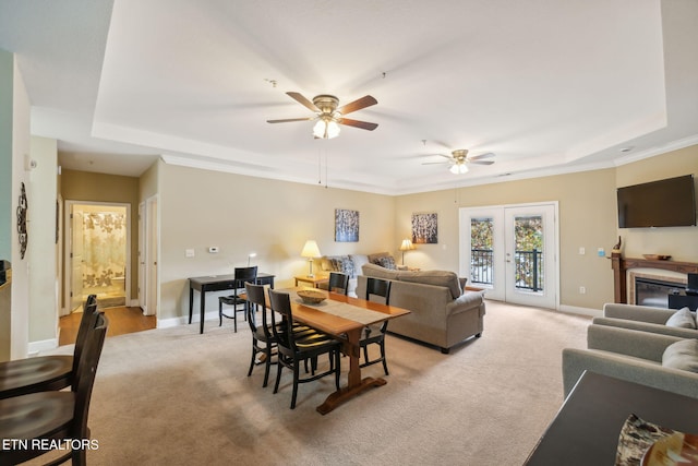 carpeted living room featuring a tray ceiling, ceiling fan, french doors, and crown molding