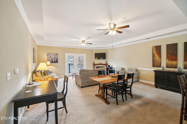 carpeted dining area featuring french doors, a tray ceiling, ceiling fan, and ornamental molding