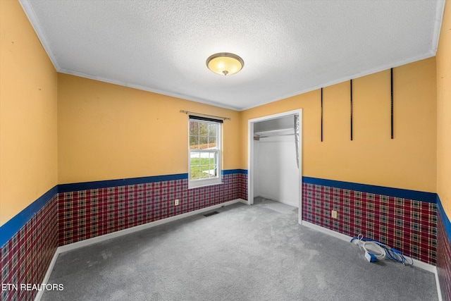 spare room with carpet, a textured ceiling, and ornamental molding