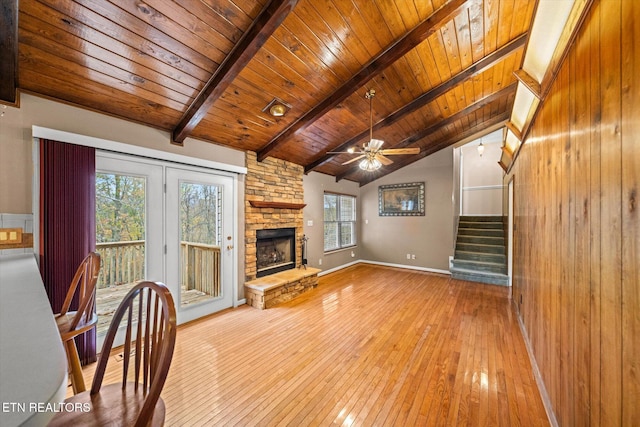 unfurnished living room with vaulted ceiling with beams, wooden ceiling, a wealth of natural light, and light hardwood / wood-style flooring