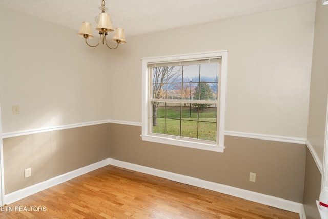 spare room featuring a chandelier and hardwood / wood-style flooring