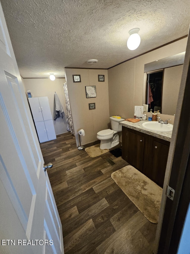 bathroom with toilet, vanity, a textured ceiling, and hardwood / wood-style flooring