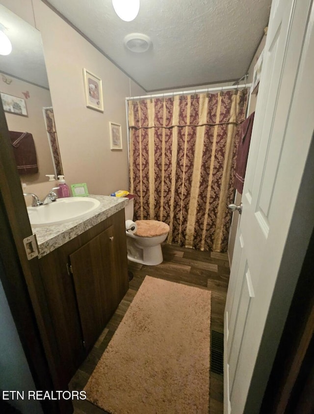 bathroom with toilet, vanity, a textured ceiling, and hardwood / wood-style flooring