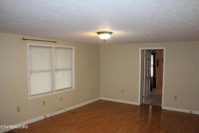 unfurnished room featuring a textured ceiling and dark hardwood / wood-style floors