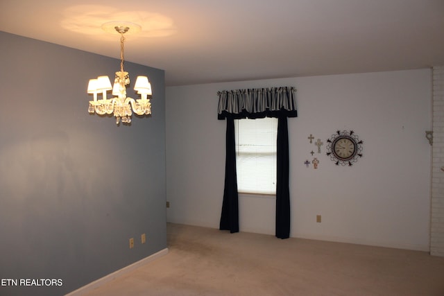 carpeted empty room featuring an inviting chandelier