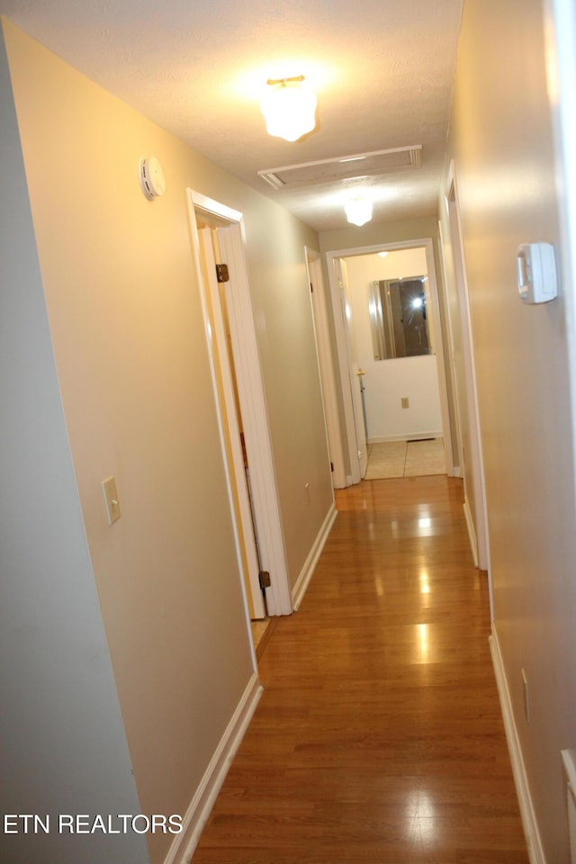 corridor with hardwood / wood-style floors and a textured ceiling