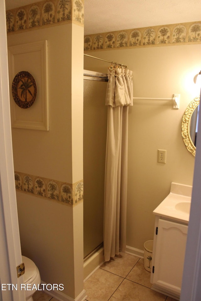 bathroom with tile patterned floors, vanity, toilet, and a shower with door