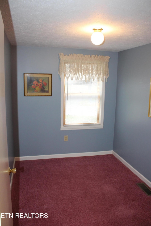 carpeted empty room with a textured ceiling