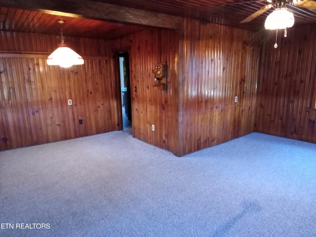 spare room with beam ceiling, carpet floors, wooden walls, and wood ceiling