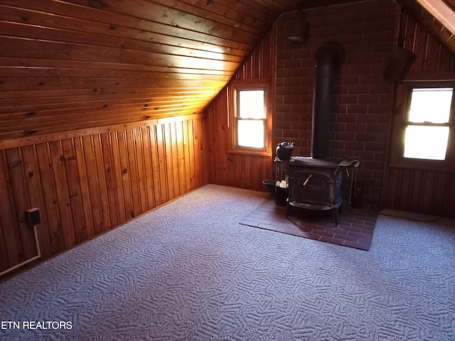 additional living space featuring wooden ceiling, a wood stove, wooden walls, and vaulted ceiling