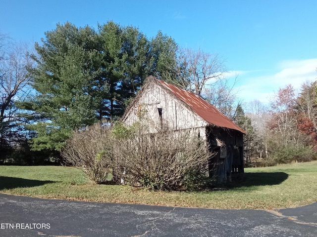 view of side of home with an outbuilding and a yard