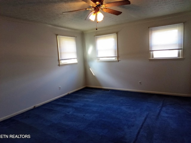 spare room featuring ceiling fan, dark carpet, and a textured ceiling