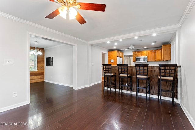 kitchen with kitchen peninsula, dark hardwood / wood-style flooring, ornamental molding, a breakfast bar, and white refrigerator