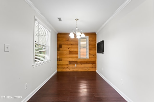 unfurnished dining area with a chandelier, dark wood-type flooring, wood walls, and ornamental molding