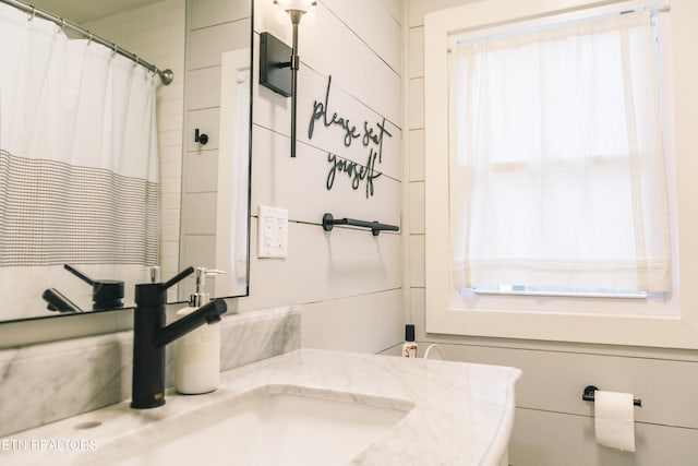 bathroom with a shower with shower curtain, vanity, and a healthy amount of sunlight