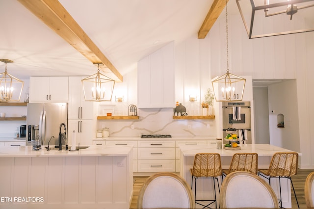 kitchen with hardwood / wood-style floors, vaulted ceiling with beams, decorative light fixtures, white cabinetry, and stainless steel appliances