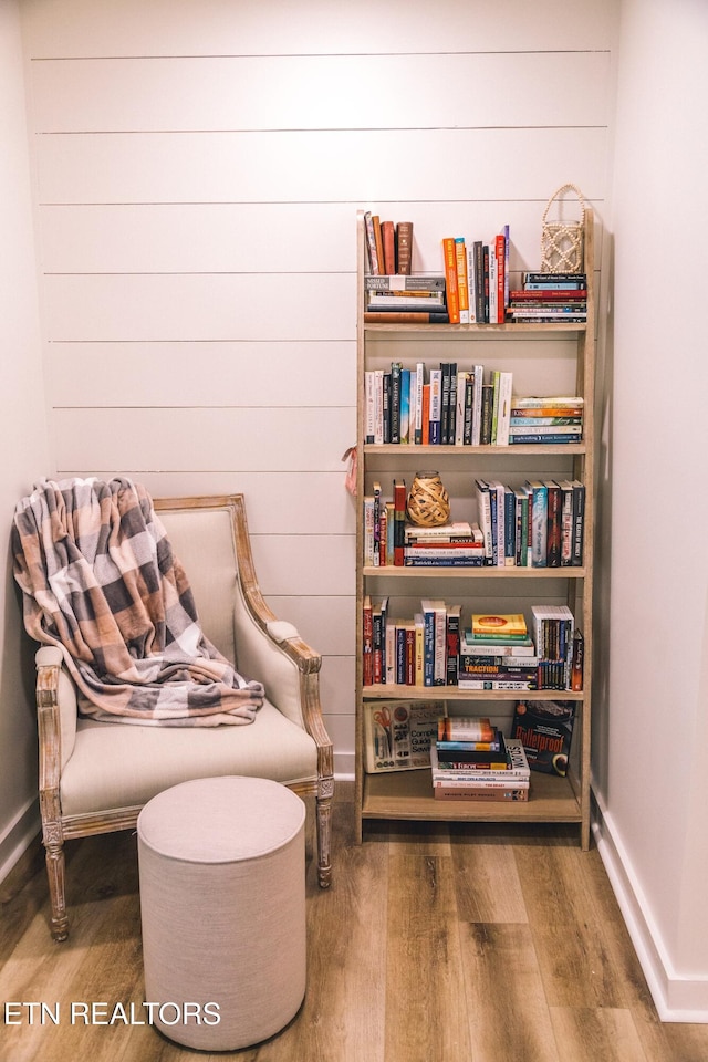 sitting room featuring wood walls and hardwood / wood-style floors