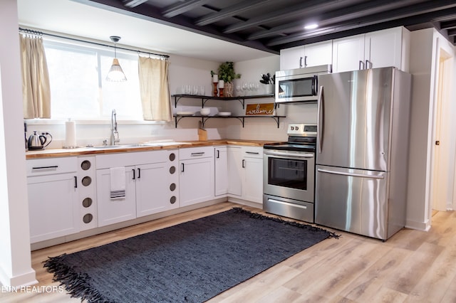 kitchen with wood counters, white cabinetry, hanging light fixtures, and appliances with stainless steel finishes