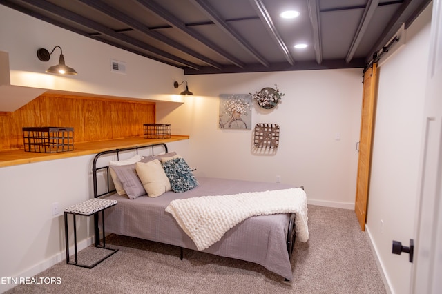 carpeted bedroom with a barn door and beam ceiling