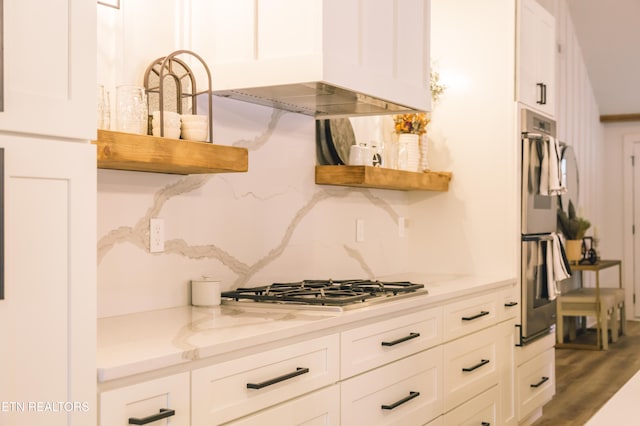 kitchen featuring white cabinets, appliances with stainless steel finishes, hardwood / wood-style flooring, and light stone counters