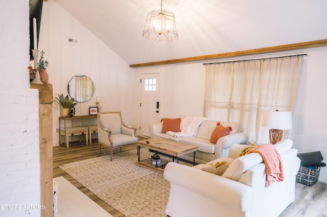 living room with a chandelier, light wood-type flooring, vaulted ceiling, and wood walls