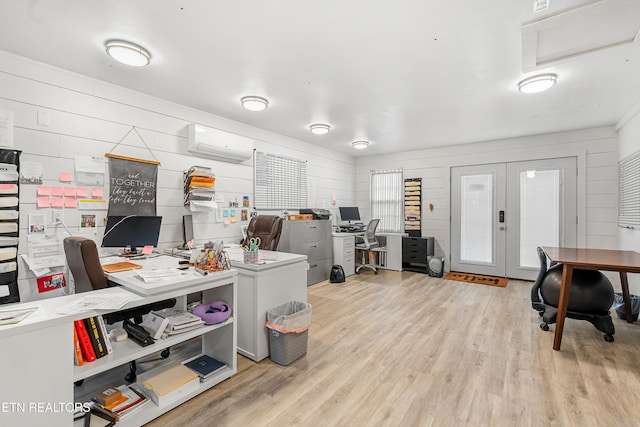 home office featuring a wall unit AC, wood walls, french doors, and light wood-type flooring