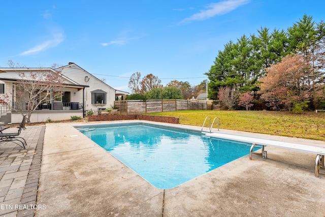 view of swimming pool featuring a yard, a patio, and a diving board