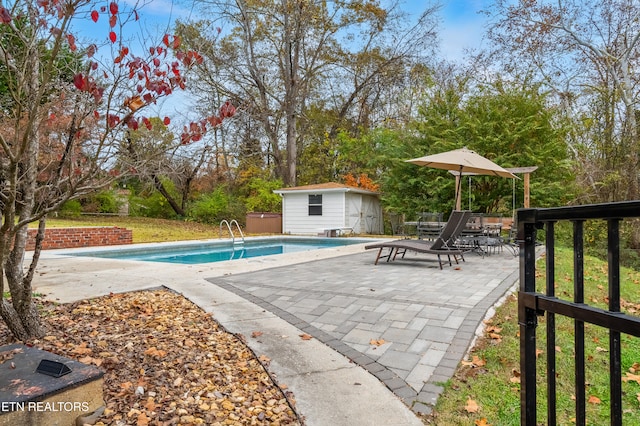 view of swimming pool with a jacuzzi, an outbuilding, and a patio area