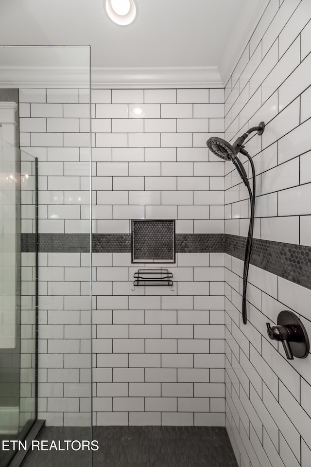 bathroom with a tile shower and ornamental molding