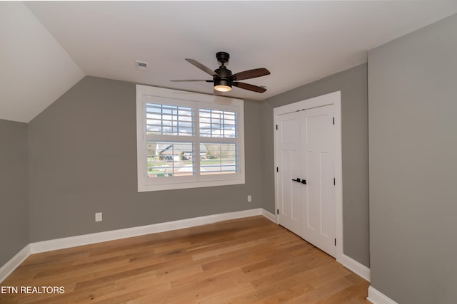 unfurnished bedroom featuring ceiling fan, light hardwood / wood-style floors, vaulted ceiling, and a closet