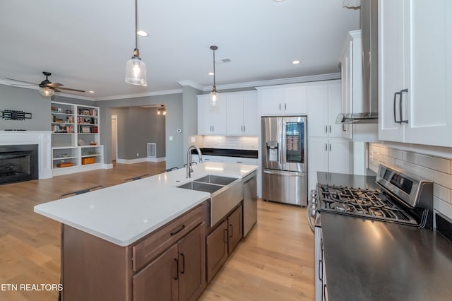 kitchen featuring sink, decorative light fixtures, a kitchen island with sink, white cabinets, and appliances with stainless steel finishes