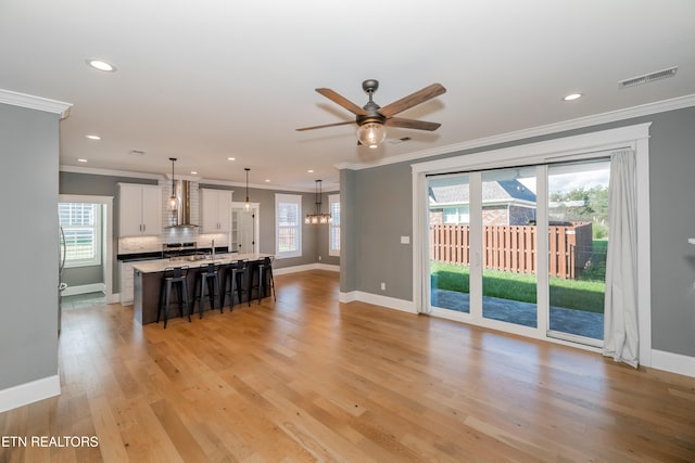 living room featuring crown molding, a wealth of natural light, and light hardwood / wood-style flooring