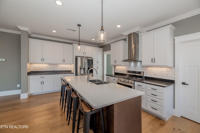 kitchen featuring sink, wall chimney exhaust hood, light wood-type flooring, and appliances with stainless steel finishes