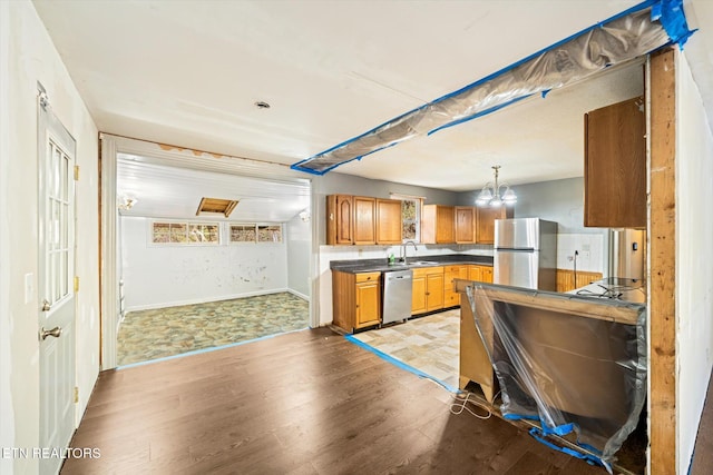 kitchen featuring appliances with stainless steel finishes, light wood-type flooring, hanging light fixtures, and sink