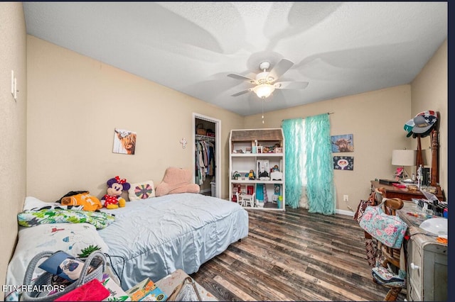 bedroom featuring dark wood-type flooring, ceiling fan, a closet, and a walk in closet