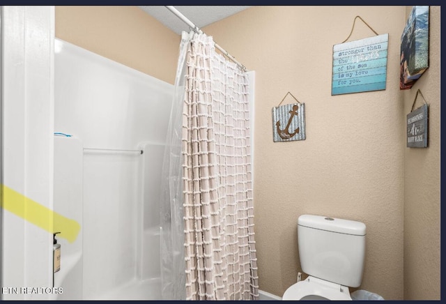 bathroom featuring a shower with curtain and toilet