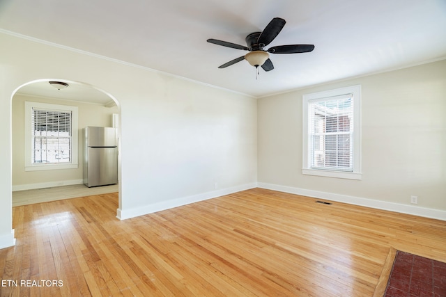 unfurnished room featuring ceiling fan, ornamental molding, a healthy amount of sunlight, and light hardwood / wood-style floors