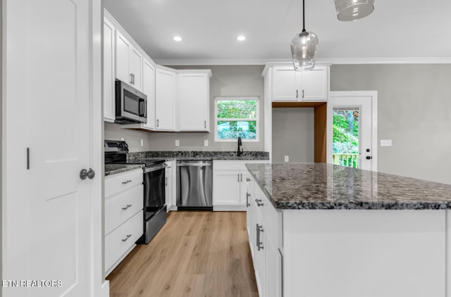 kitchen with appliances with stainless steel finishes, ornamental molding, light hardwood / wood-style flooring, white cabinetry, and hanging light fixtures