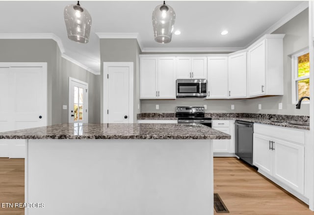 kitchen with white cabinetry, sink, stainless steel appliances, decorative light fixtures, and a kitchen island