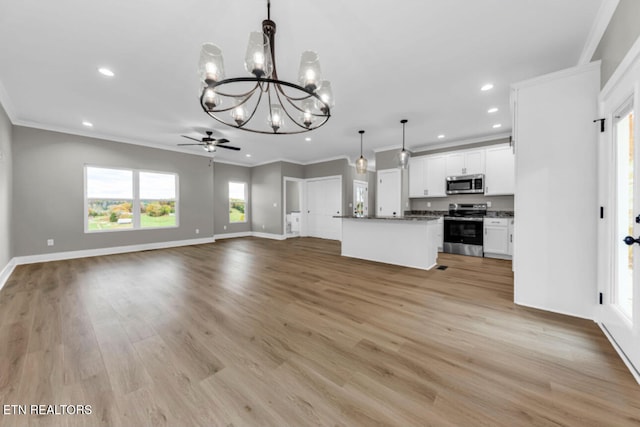 kitchen featuring appliances with stainless steel finishes, crown molding, decorative light fixtures, white cabinets, and light wood-type flooring