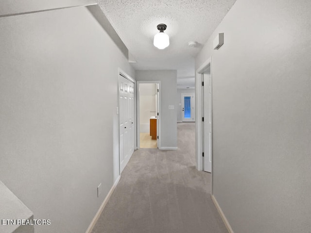 hall featuring light colored carpet and a textured ceiling