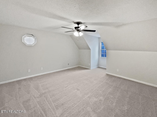 additional living space with carpet flooring, ceiling fan, lofted ceiling, and a textured ceiling