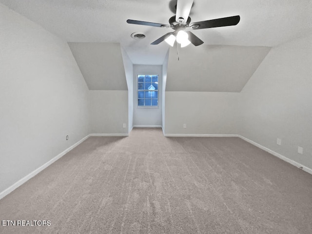 additional living space with a textured ceiling, ceiling fan, light colored carpet, and lofted ceiling