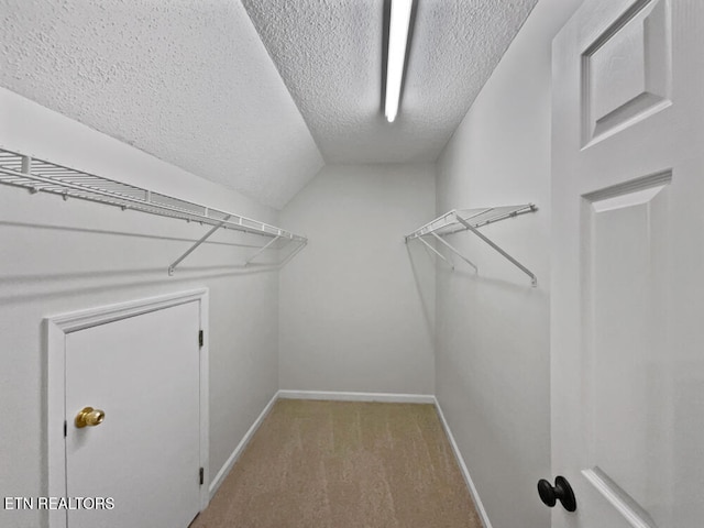 walk in closet featuring light colored carpet and vaulted ceiling