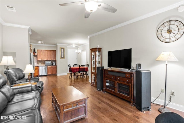 living room featuring ceiling fan with notable chandelier, wood-type flooring, and ornamental molding